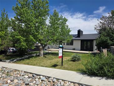 Charming single-story home featuring a manicured front yard, lush landscaping and a 'For Sale' sign at 9040 Yucca Way, Thornton, CO 80229