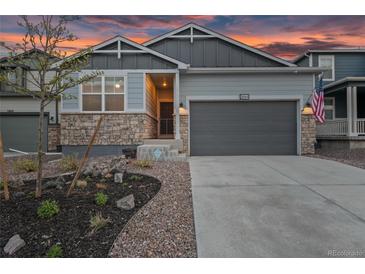 Charming home with stone accents, a two-car garage, and professional landscaping set against a colorful sky at dusk at 3844 Sandy Vista Ln, Castle Rock, CO 80104