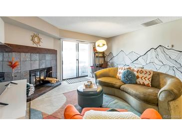 Inviting living room with stone fireplace, stylish decor, and sliding glass doors to a balcony at 14208 E 1St Dr # C1, Aurora, CO 80011