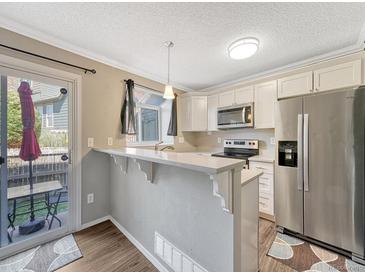 Bright kitchen featuring stainless steel appliances and access to the patio via a sliding glass door at 17427 E Rice Cir # C, Aurora, CO 80015