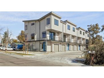 Modern townhomes with attached garages, balconies, and contemporary design stand out against a blue sky at 1682 Tabor St, Lakewood, CO 80215