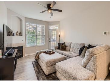 Cozy living room with fireplace, ceiling fan, and sectional sofa with tray and rug at 5755 N Genoa Way # 14-105, Aurora, CO 80019