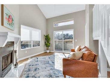 Bright living room featuring vaulted ceilings, a modern fireplace, and sliding glass doors to the outdoor at 1820 Newland Ct # 201, Lakewood, CO 80214