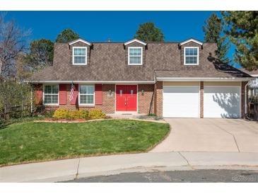 Charming two-story brick home with dormer windows, red door, manicured lawn, and attached two car garage at 7169 S Grape Ln, Centennial, CO 80122