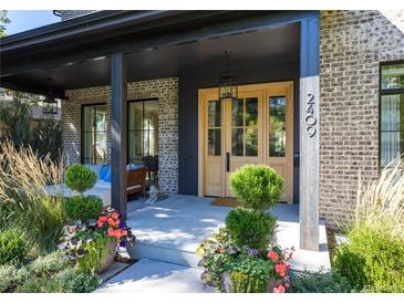 Inviting covered front entry featuring light brick, wood doors, and curated plantings at 2409 S Fillmore St, Denver, CO 80210