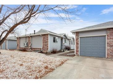 Charming single-story home features a detached garage, gray siding, and a brick accent wall on a cloudy day at 2027 Terry St # 1, Longmont, CO 80501