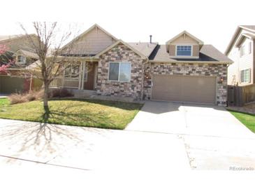 Charming two-story home featuring a stone facade, a well-manicured lawn, and an attached two-car garage at 21444 E Lehigh Ave, Aurora, CO 80013