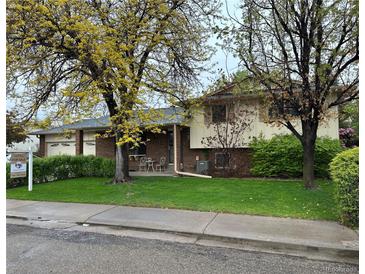 Charming brick and siding home with mature landscaping and a cozy front patio area at 710 S Grand Ave, Fort Lupton, CO 80621