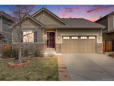 Charming home featuring stone accents, a two-car garage, and manicured lawn, set against a vivid sunset sky at 12677 Fisher Dr, Englewood, CO 80112