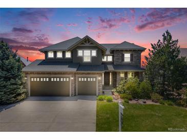 Stunning two-story home featuring a three-car garage, stone accents, and beautifully landscaped front yard against a gorgeous sky at 26764 E Canyon Ave, Aurora, CO 80016