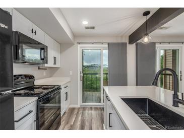 Bright kitchen with modern appliances, white cabinetry, and a sliding glass door to balcony at 4899 S Dudley St # 14F, Littleton, CO 80123