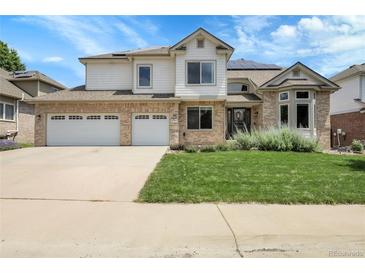 A charming two-story home features a brick and siding exterior, well-maintained lawn, and a three-car garage at 11411 W Cooper Dr, Littleton, CO 80127