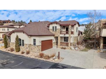 Inviting two-story home featuring a stucco and stone facade, a two car garage, and a covered balcony at 4415 Echo Ct, Larkspur, CO 80118