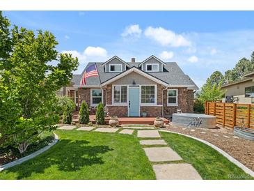 Charming stone home with blue door, dormer windows, American flag, and a well-manicured lawn at 895 Nile Ct, Golden, CO 80401