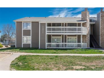 Two-story condo building with a white railed porch and green lawn at 18071 E Kentucky Ave # 203, Aurora, CO 80017