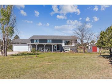 Charming two-story home with a covered front porch, spacious yard, and mature trees, perfect for serene country living at 36901 View Ridge Dr, Elizabeth, CO 80107