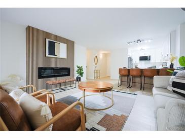 Bright living room featuring modern fireplace, stylish decor, and open-concept layout with breakfast bar at 3450 S Poplar St # 307, Denver, CO 80224