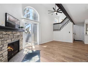 Bright living room features a stone fireplace, wood floors, and vaulted ceilings with a large window at 921 S Zeno Way # 201, Aurora, CO 80017