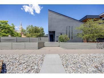Modern home featuring a landscaped front yard with a secure fence and unique architectural design at 2801 Lawrence St, Denver, CO 80205