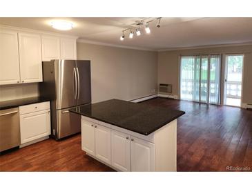 Bright kitchen with an island, stainless steel appliances, and wooden floors that flow into an inviting living space at 9300 E Center Ave # 6A, Denver, CO 80247