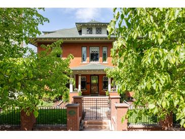 Charming brick two-story home with a landscaped front yard, gated entrance and covered front porch at 1275 N Franklin St, Denver, CO 80218