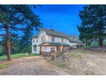 Charming white two-story home featuring stone accents, lush greenery and a well-maintained front yard at 9310 S Watson Gulch Rd, Littleton, CO 80127