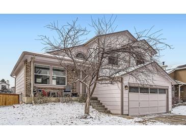 Charming two-story home with attached garage, covered porch, and snow-covered yard at 6366 Nassau Ct, Highlands Ranch, CO 80130