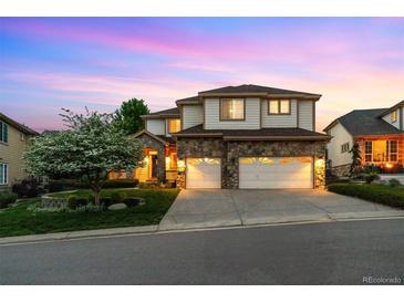 Beautiful two-story home featuring a stone facade, spacious garage, manicured lawn, and beautiful landscaping at 6427 S Tibet St, Aurora, CO 80016