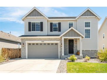 Charming two-story home with stone accents, gray siding, an attached two-car garage and a manicured front lawn at 7678 S Old Hammer Way, Aurora, CO 80016