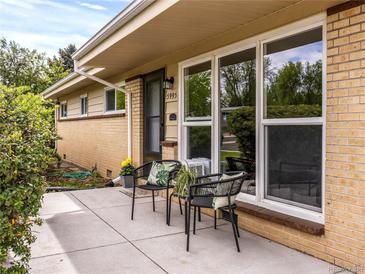 Charming home featuring a cozy front porch with seating, large window, and manicured landscaping at 5995 Estes St, Arvada, CO 80004