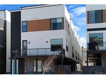 Modern townhome featuring a mix of white and wood paneling, black accents, and a compact front balcony at 1930 Hooker St # 3, Denver, CO 80204