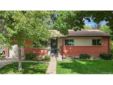 Charming brick home featuring a well-manicured lawn, a flower-adorned entrance, and a welcoming wreath on the door at 6371 Brooks Dr, Arvada, CO 80004