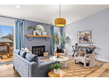 Cozy living room features a fireplace, modern furniture, and a walk out to the deck at 2484 E 101St Ct, Thornton, CO 80229