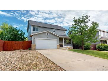 Charming two-story home featuring a well-maintained lawn, a two car garage, and a cozy front porch at 2160 Ance St, Strasburg, CO 80136