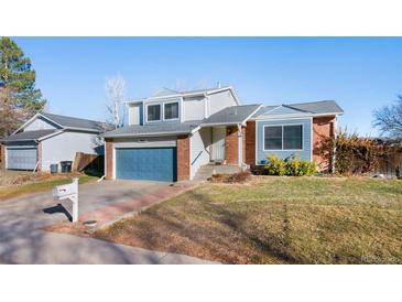 Charming two-story home featuring a blue garage door, brick accents, and a well-maintained front yard at 19697 E Flora Pl, Aurora, CO 80013