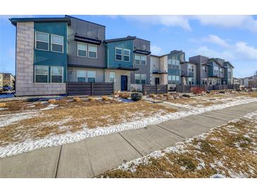 Modern townhouses with gray and teal exterior, private fenced yards, and a sidewalk at 4758 Kittredge St # 2, Denver, CO 80239