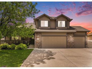 Inviting two-story home featuring a stone facade, attached garage, and manicured lawn at 9650 Raven St, Firestone, CO 80504