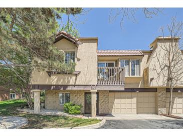 Inviting townhome with a tan exterior, balcony, mature trees, and a two-car attached garage at 2695 S Ames Way # 1, Lakewood, CO 80227