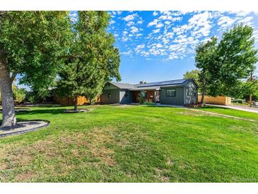 Landscaped front yard and charming single-story home with solar panels in a lush green setting at 5601 E Colorado Ave, Denver, CO 80224