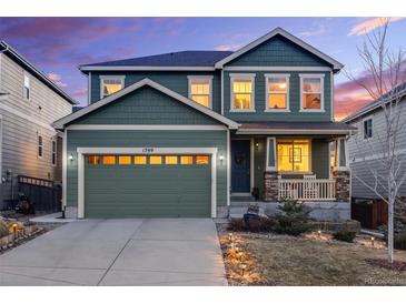 Charming two-story home featuring a two-car garage, covered porch, and manicured lawn at twilight at 1399 Morningview Ln, Castle Rock, CO 80109