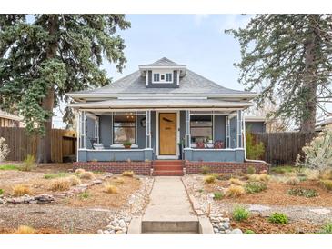 Charming gray home with a landscaped front yard, covered porch, and inviting walkway at 4824 Knox Ct, Denver, CO 80221