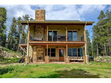 Charming home with a stone chimney, covered patio, and a balcony perfect for enjoying the outdoors at 1555 Three Peaks Rd, Golden, CO 80403