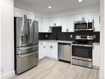 Modern kitchen featuring stainless steel appliances and dark hexagon backsplash at 4899 S Dudley # 1I, Littleton, CO 80123