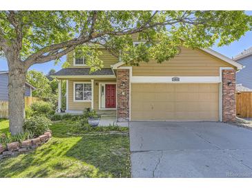 Charming tan two-story home with a red front door, brick accents, and a well-manicured lawn at 12616 Country Meadows Dr, Parker, CO 80134