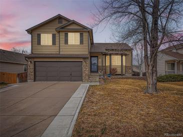Charming two-story home featuring stone accents, a two-car garage, and manicured landscaping at 11395 E 116Th Dr, Commerce City, CO 80640