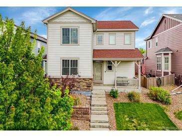 Inviting two-story home with stone accents, landscaped front yard, and charming covered porch with a red roof at 3810 Cadence Dr, Castle Rock, CO 80109