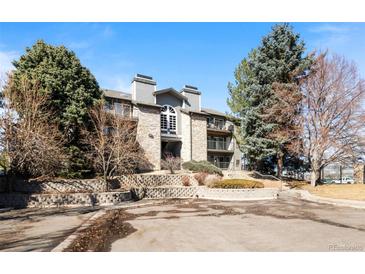 Charming condo building featuring stone accents, mature trees, and a well-maintained landscape at 2575 S Syracuse Way # L306, Denver, CO 80231