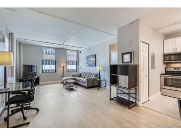 Bright living room features an open layout, with neutral decor, hardwood floors, and large windows at 444 17Th St # 701, Denver, CO 80202