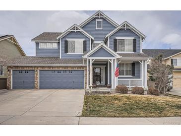 Charming two-story home features a well-maintained lawn and a three-car garage, with classic blue siding at 10551 Redcone Way, Highlands Ranch, CO 80130