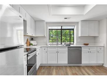 Bright kitchen featuring white cabinets, stainless steel appliances, and a window with a view of the trees at 12662 E Warren Dr # F, Aurora, CO 80014